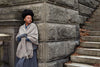 Woman leaning against a stone wall with steps in the background