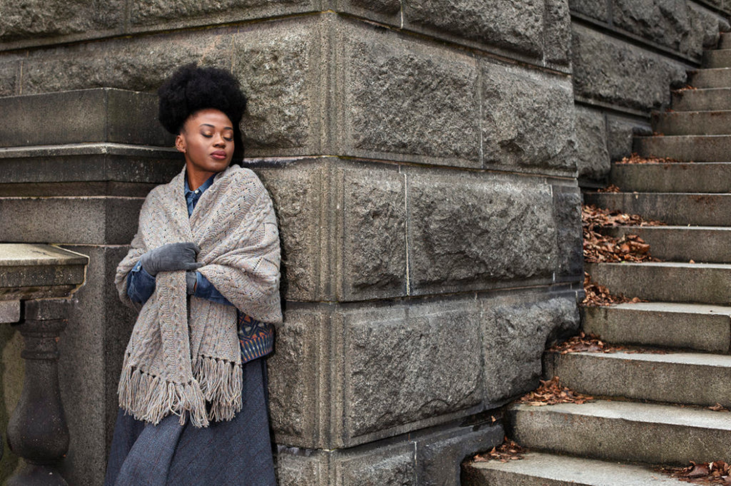 Woman leaning against a stone wall with steps in the background