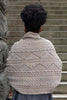 Person wearing a patterned knitted sweater standing on stone steps.