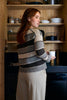 Woman in a striped sweater holding a mug in a kitchen.