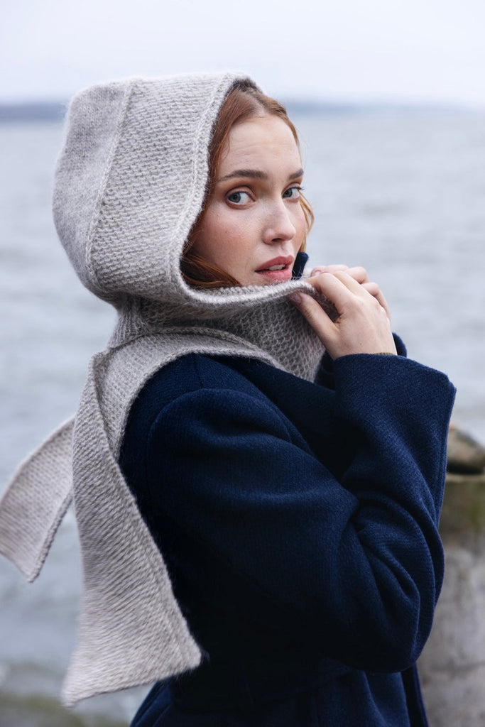 Woman wearing a hooded garment by the sea