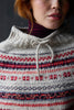 Person wearing a knitted sweater with a pattern of red, blue, and gray.