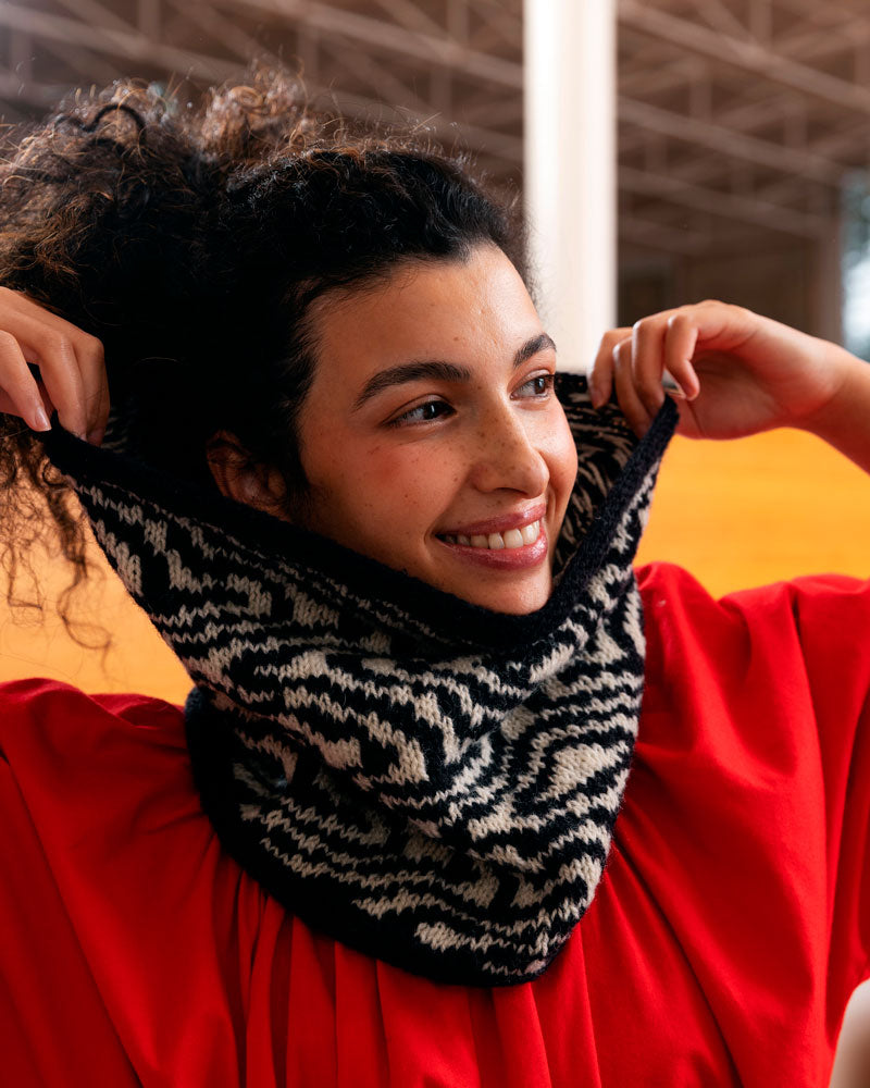 Woman wearing a black and white patterned knitted scarf with a red background