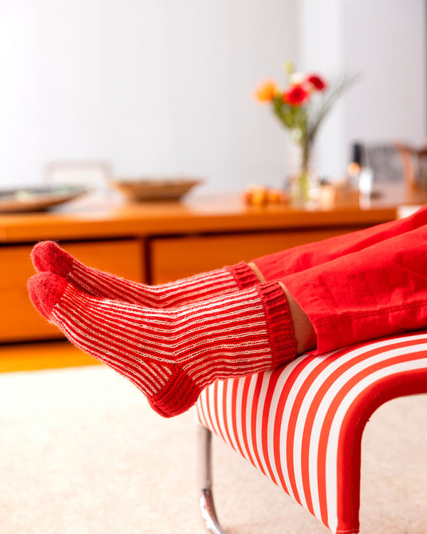 Person wearing red and white striped socks with a blurred indoor background