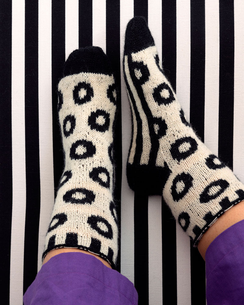 White socks with black leopard print pattern on a black and white striped background