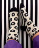 White socks with black leopard print pattern on a black and white striped background