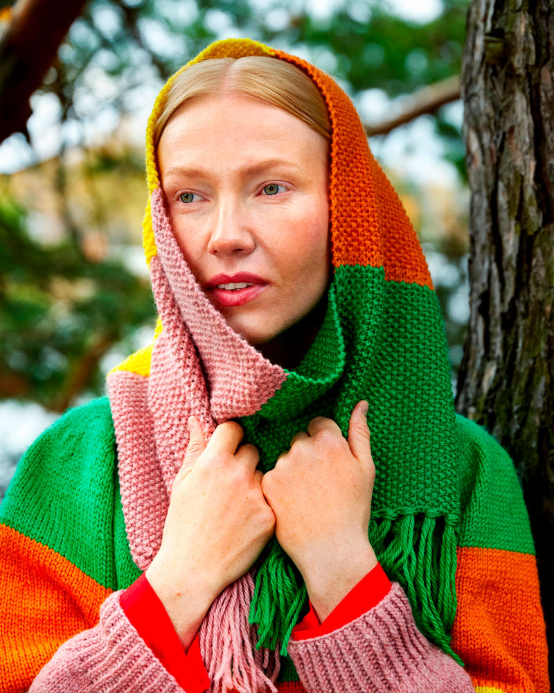Person wearing a colorful scarf and sweater in a forest setting