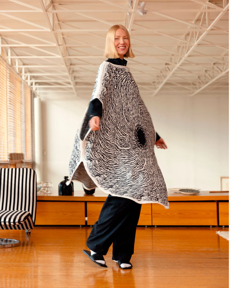 Person wearing a large black and white patterned garment in an indoor setting