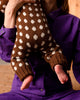 Person wearing a brown sweater with white polka dots, held by another person in a purple shirt.