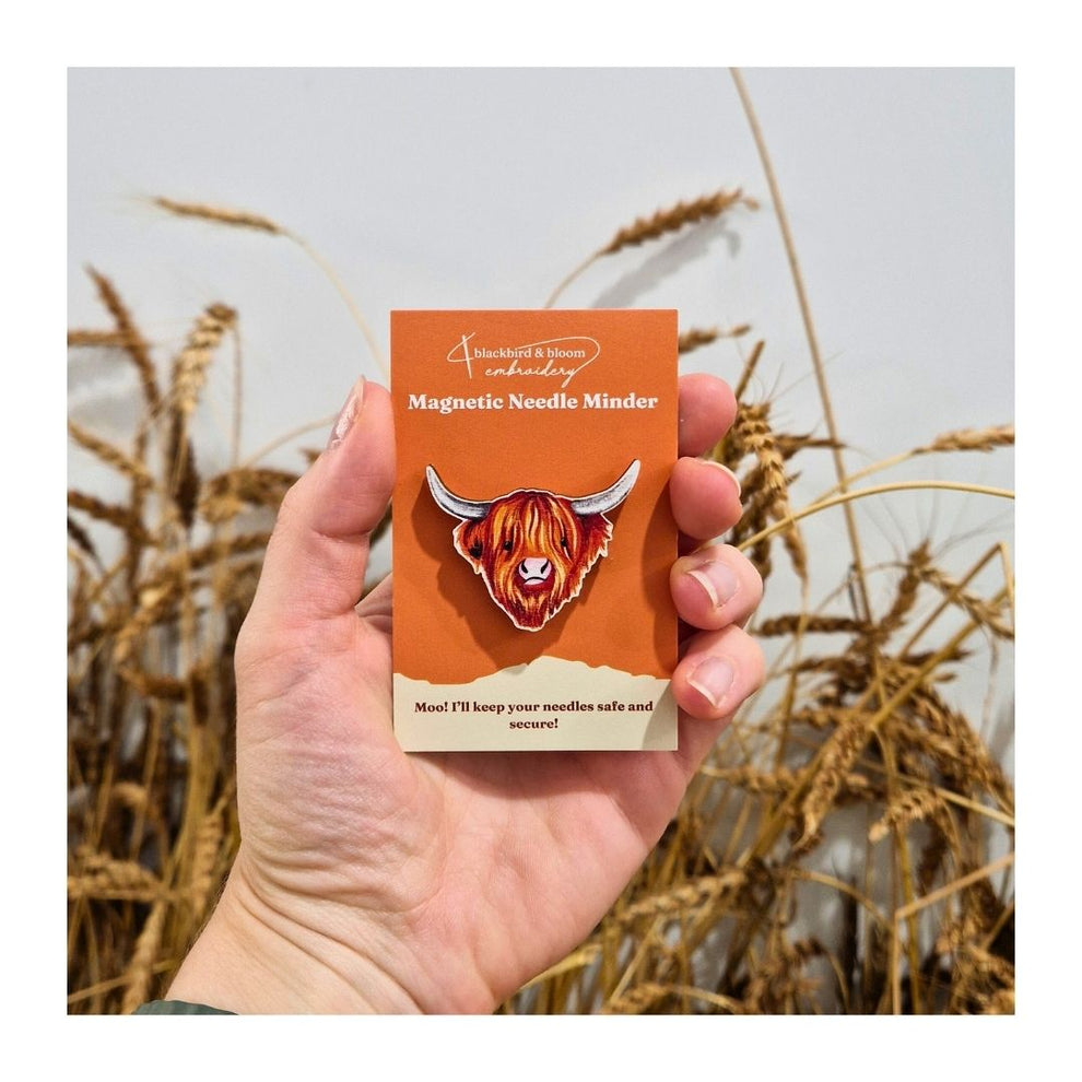 A highland cow shaped needle minder on a backing card held in someone's hand.