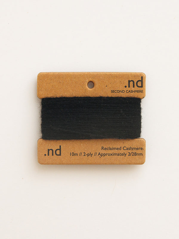 Black cashmere yarn on a cardboard holder with 'nd' branding on a white background