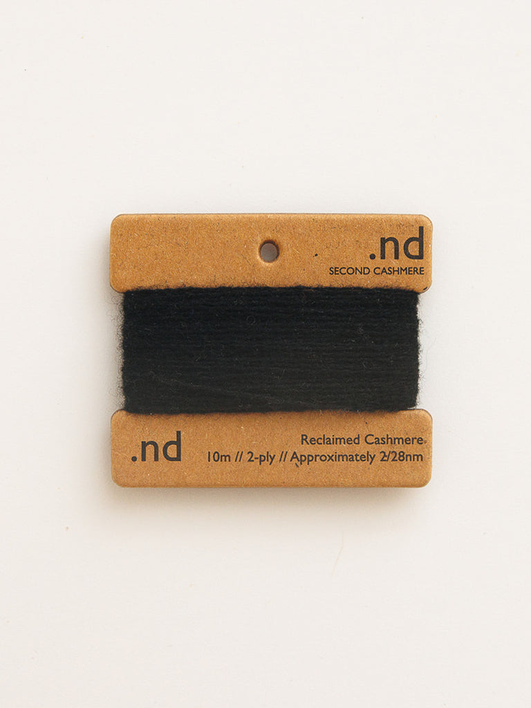 Black cashmere yarn on a cardboard holder with 'nd' branding on a white background