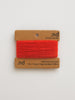 Red yarn on a cardboard holder with 'nd' branding on a light gray background