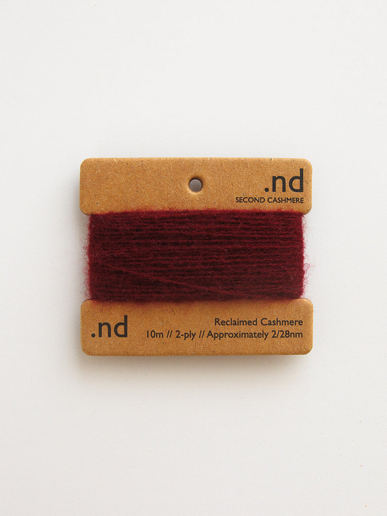 Red cashmere yarn on a branded card with 'nd' logo on a white background