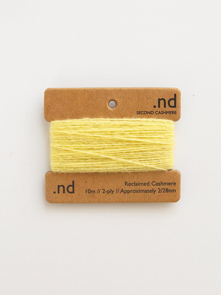 Yellow yarn on a brown card with 'nd' branding on a white background