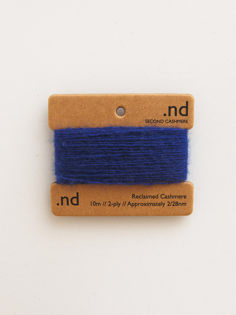 Blue yarn on a brown card with 'nd' branding on a white background