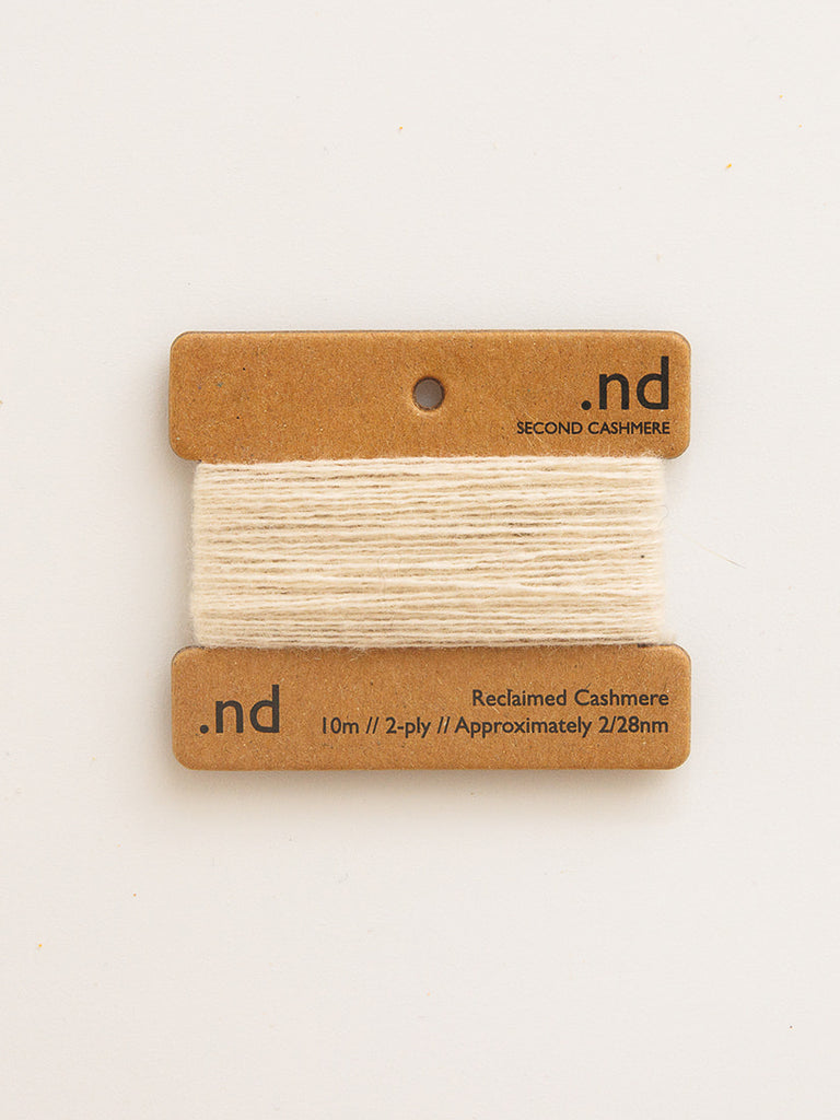 Reclaimed cashmere yarn on a branded card with 'nd' logo on a light beige background