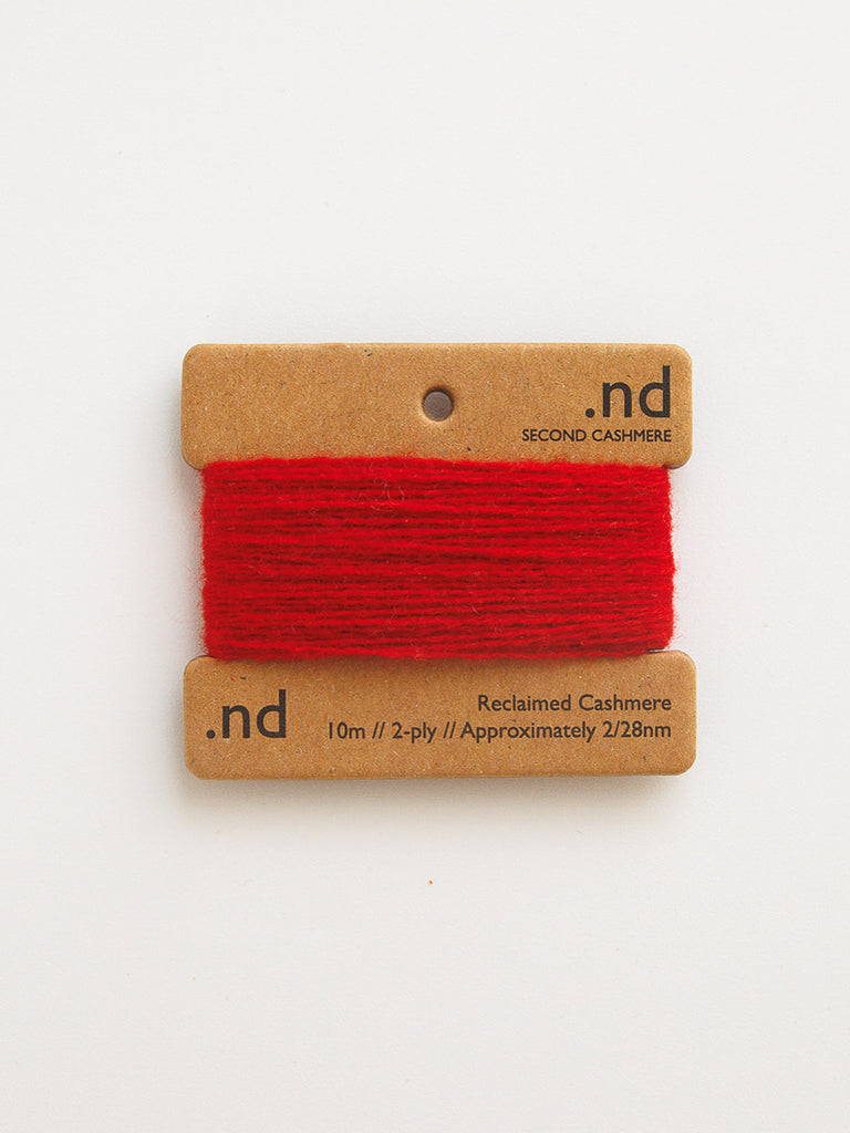 Red yarn on a brown card with 'nd' branding on a white background