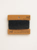 Black cashmere sample on a branded card with 'nd' on a beige background