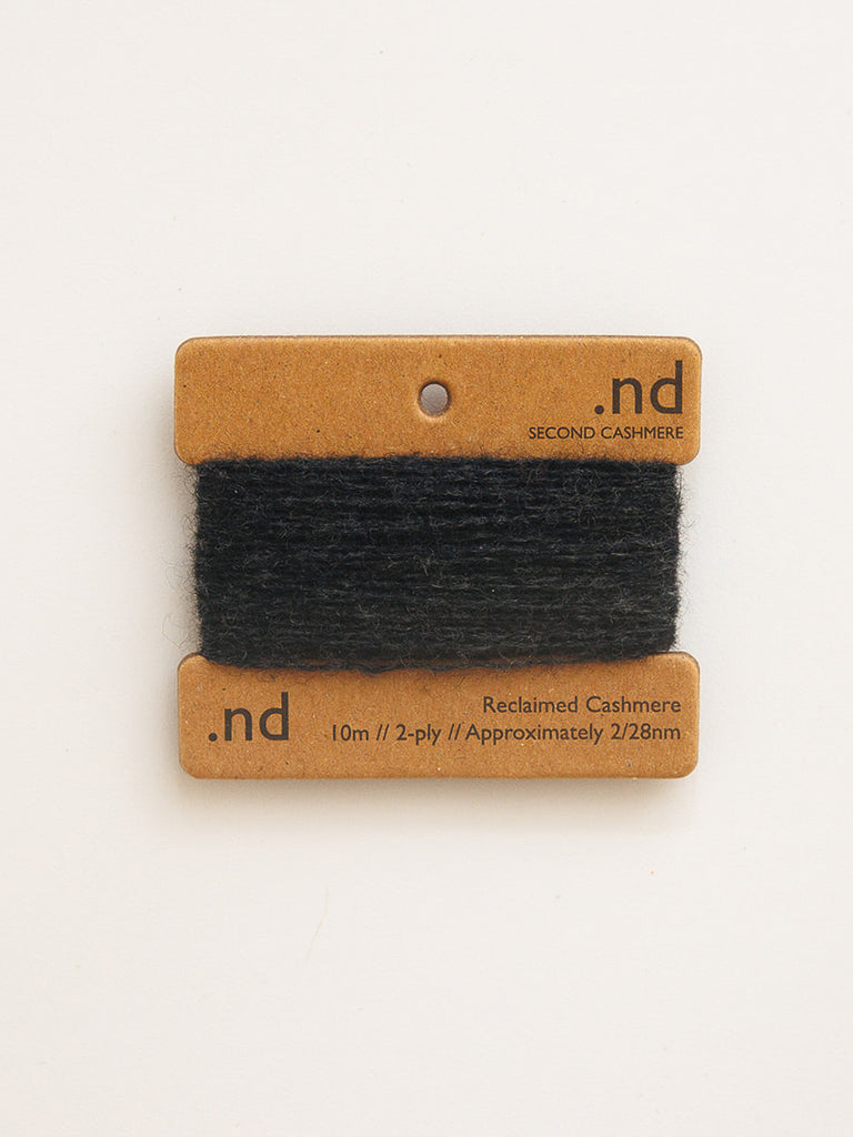 Black cashmere sample on a branded card with 'nd' on a beige background