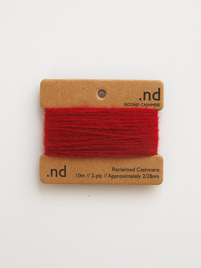 Red yarn on a brown card with 'nd' branding on a white background