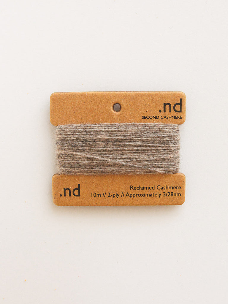 Card with brown and gray yarn swatch on a beige background