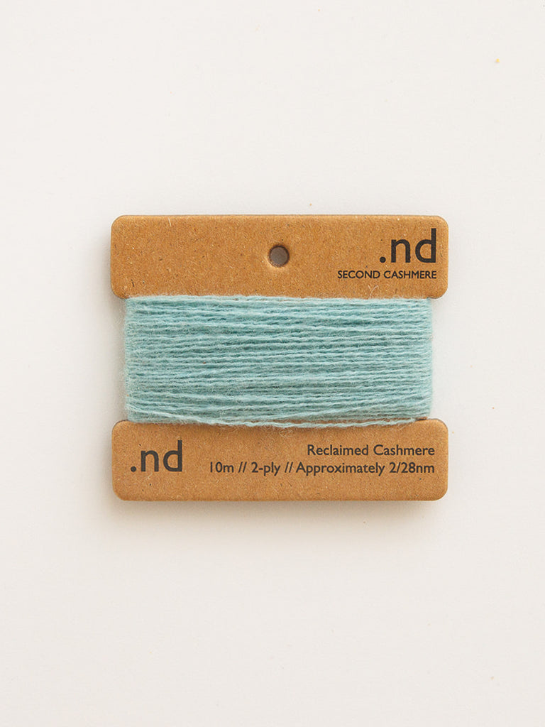 Teal yarn on a cardboard holder with 'nd' branding on a white background