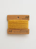 Mustard yellow yarn on a branded spool with 'nd' label on a white background