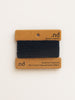 Black yarn on a branded brown card with 'nd' branding on a beige background