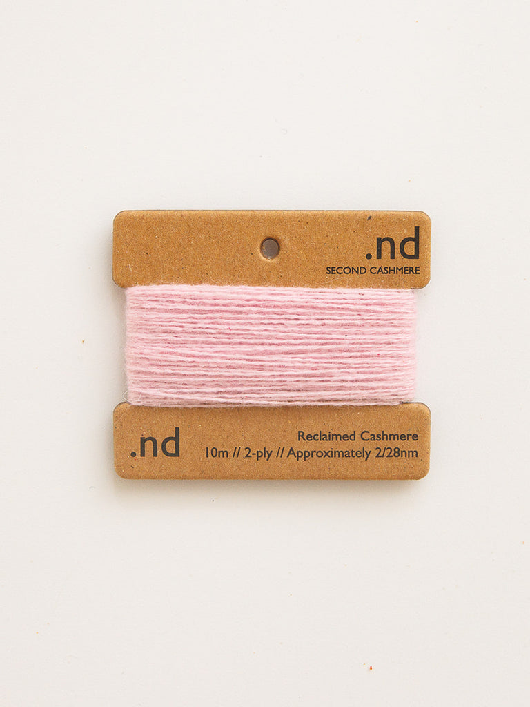 Pink yarn on a 'nd' branded card with product details on a white background