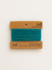Teal yarn on a brown card with 'nd' branding on a white background