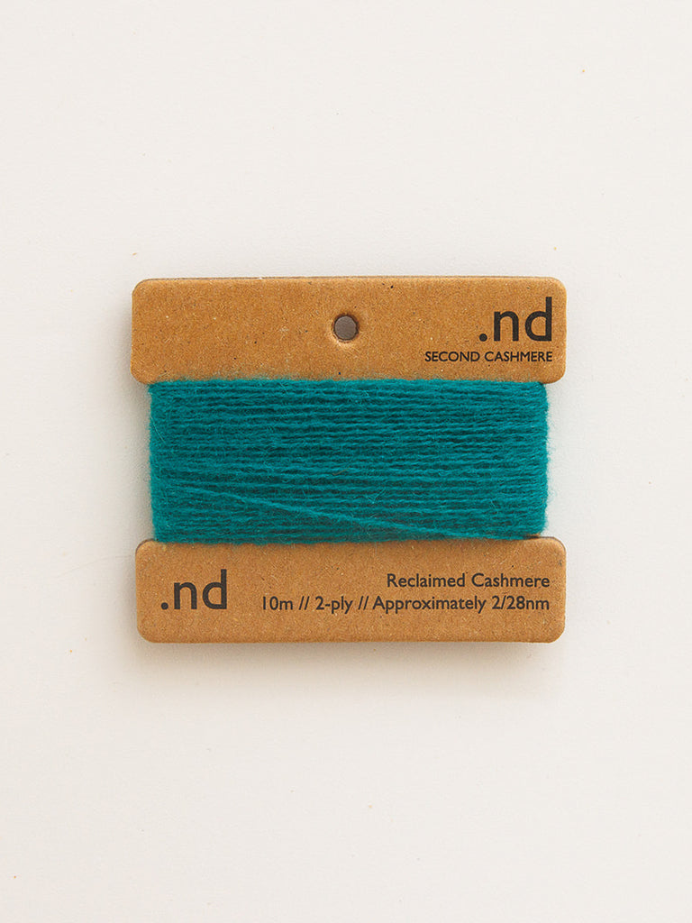 Teal yarn on a brown card with 'nd' branding on a white background