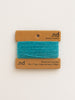 Turquoise yarn on a branded card with 'nd' on a beige background