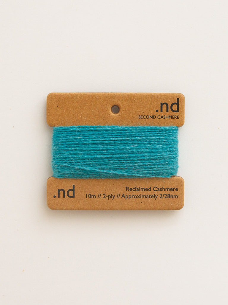Turquoise yarn on a branded card with 'nd' on a beige background
