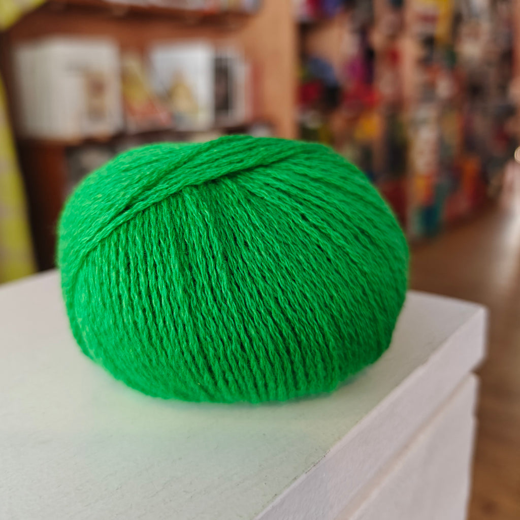 Three skeins of Gepard Cashmere Klassik yarn in orange, pink, and green colors, displayed on a surface.