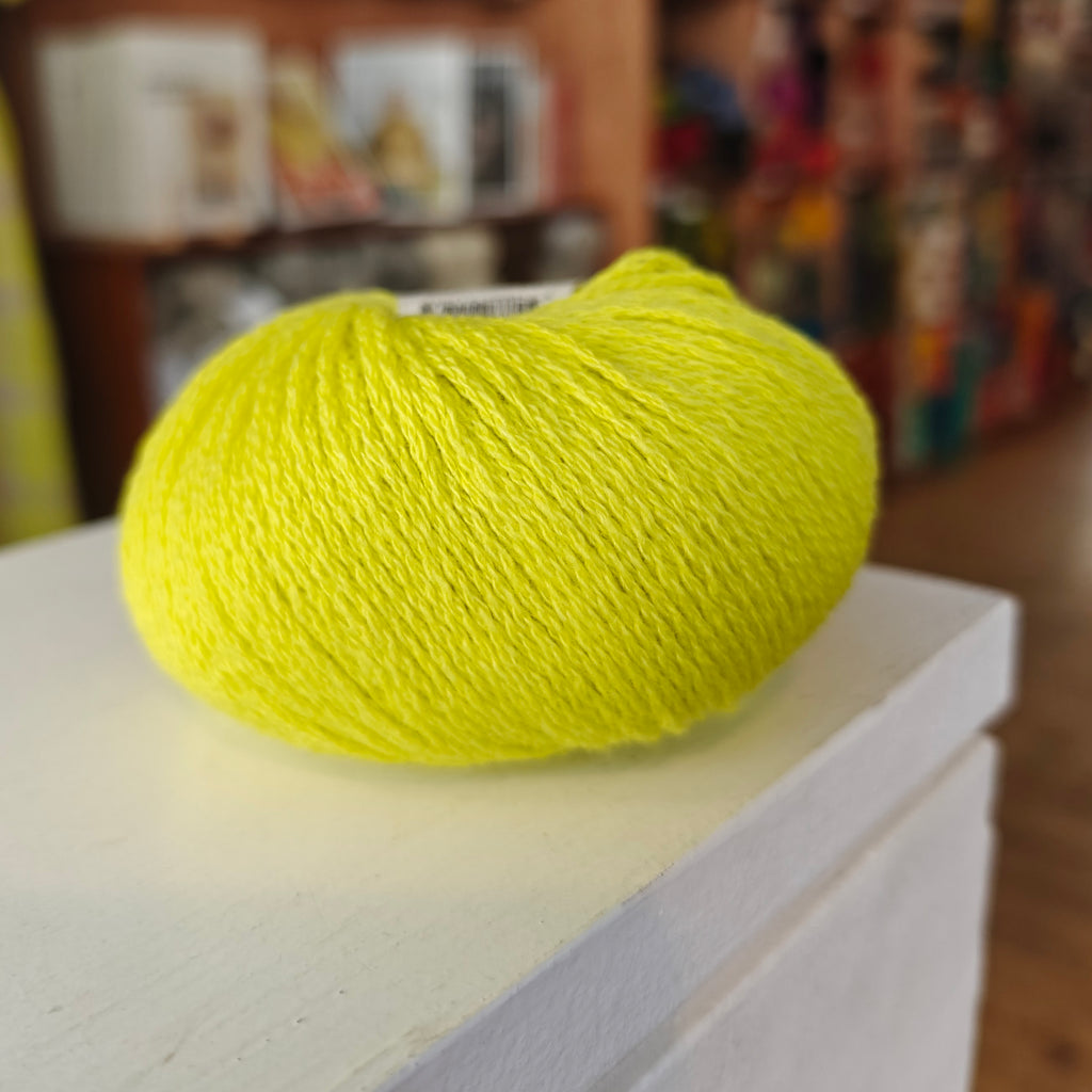 Three skeins of Gepard Cashmere Klassik yarn in orange, pink, and green colors, displayed on a surface.