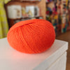 Three skeins of Gepard Cashmere Klassik yarn in orange, pink, and green colors, displayed on a surface.