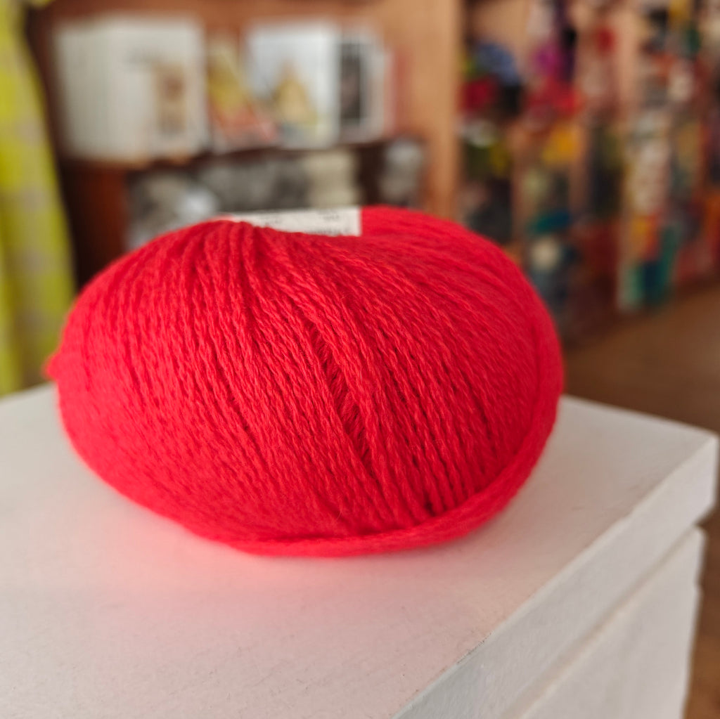 Three skeins of Gepard Cashmere Klassik yarn in orange, pink, and green colors, displayed on a surface.