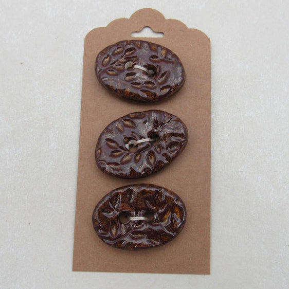 Three brown buttons on a cardboard backing against a white background