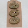 Three ceramic buttons with floral patterns on a cardboard backing against a white background
