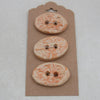 Three decorative buttons on a cardboard backing against a light gray background