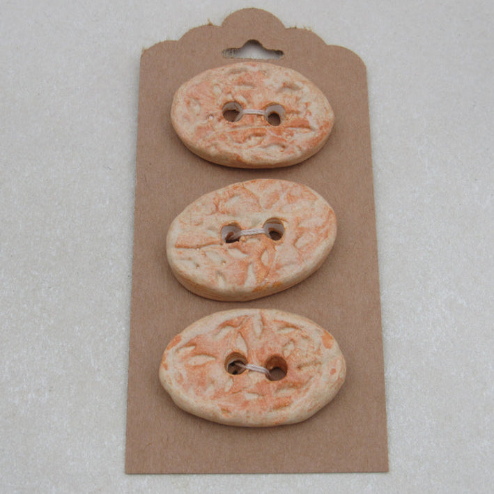Three decorative buttons on a cardboard backing against a light gray background