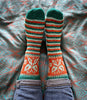 Colorful striped socks with floral patterns worn on a patterned blanket