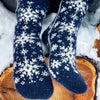 Blue and white patterned socks on a wooden log with snow in the background