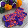 Colorful patterned socks on a wooden surface with flowers in the background