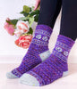Purple patterned socks worn by a person with flowers in the background