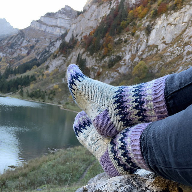 Person wearing patterned socks with a mountain and lake background