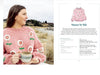 Woman wearing a pink sweater with floral patterns, holding a cup outdoors.