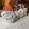 Two skeins of gray yarn on a white surface with a blurred background