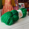 Green skein of yarn with a label on a white surface, blurred background